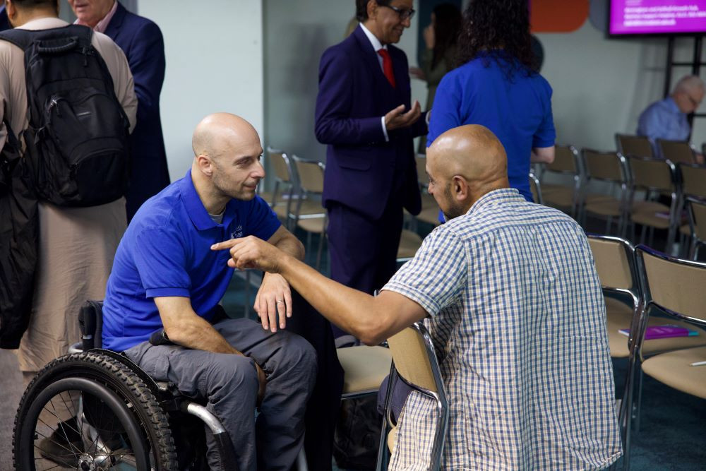 man in wheelchair networking with someone at a conference in Solihull